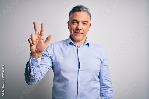 Middle age handsome grey-haired business man wearing elegant shirt over white background showing and pointing up with fingers number three while smiling confident and happy.