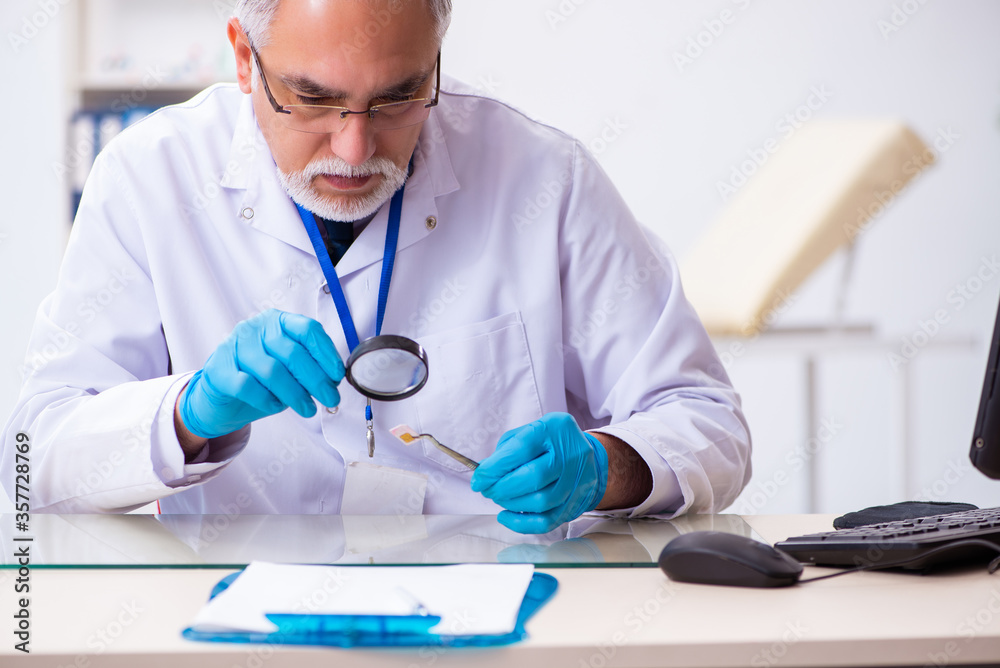 Old male expert criminologist working in the lab for evidence Old male expert criminologist working in the lab for evidence