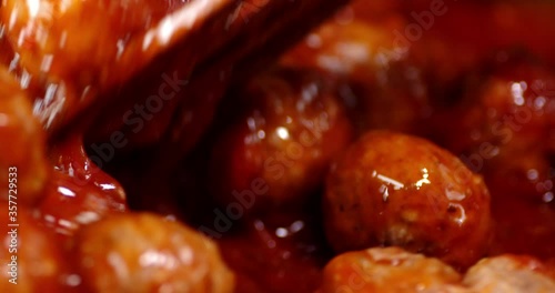 Meatballs mixed with a spatula with tomato sauce.