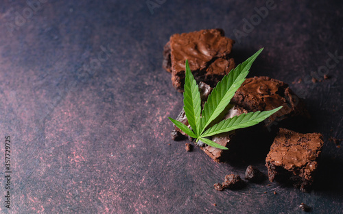 Chocolate cannabis brownies on dark background with marijuana leaf made with CBD butter. A delicious desert to impress your dinner guests and a relaxing way to end the evening.