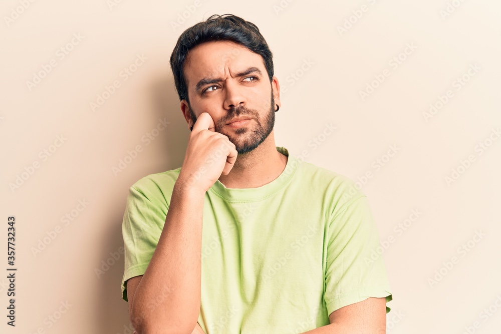 Young hispanic man wearing casual clothes thinking concentrated about doubt with finger on chin and looking up wondering