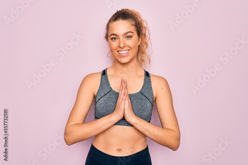 Young beautiful blonde sportswoman with blue eyes doing exercise wearing sportswear praying with hands together asking for forgiveness smiling confident.