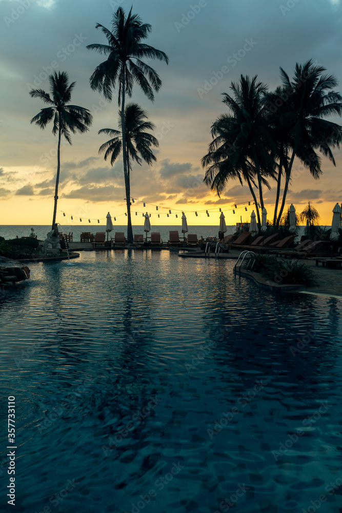 Tropical palm trees silhouetted against a dusk blue sky on the beach.