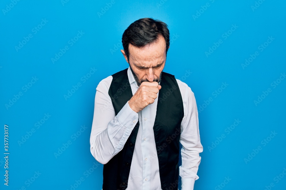 Middle age handsome man wearing elegant shirt and vest over isolated blue background feeling unwell and coughing as symptom for cold or bronchitis. Health care concept.
