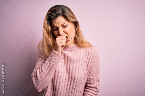 Young beautiful blonde woman wearing casual pink sweater over isolated background feeling unwell and coughing as symptom for cold or bronchitis. Health care concept.