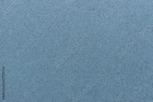 Texture of old light blue paper closeup. Structure of a matte dense cardboard wallpaper. Denim felt background