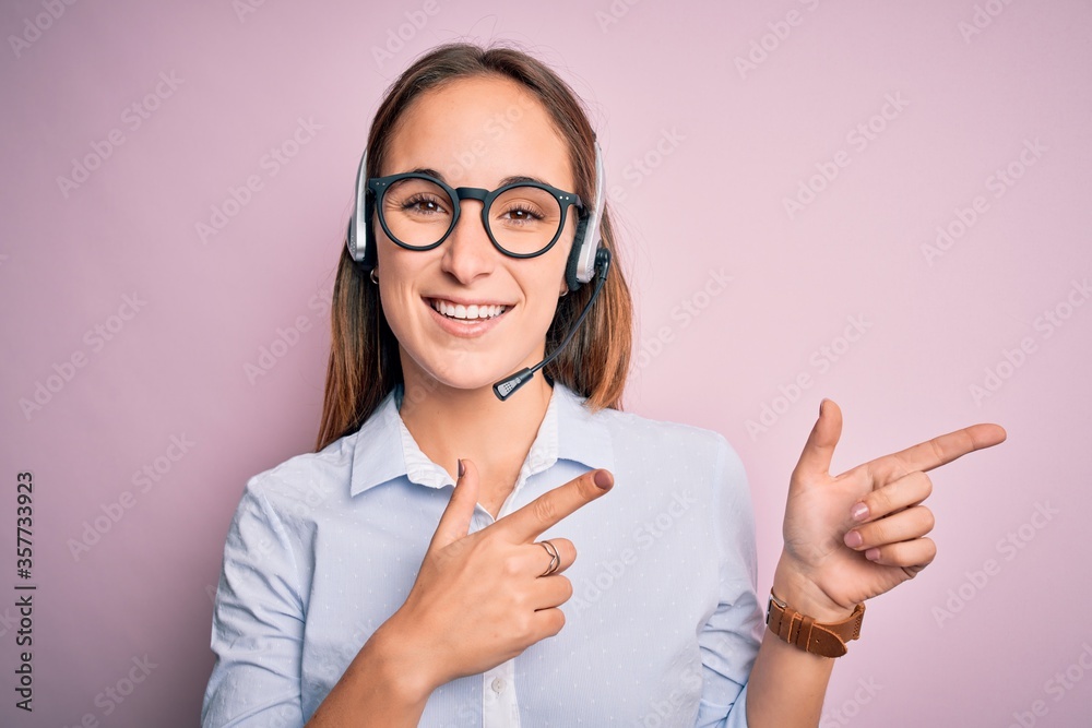 Young beautiful call center agent woman wearing glasses working using headset smiling and looking at the camera pointing with two hands and fingers to the side. Young beautiful call center agent woman wearing glasses working using headset smiling and looking at the camera pointing with two hands and fingers to the side.