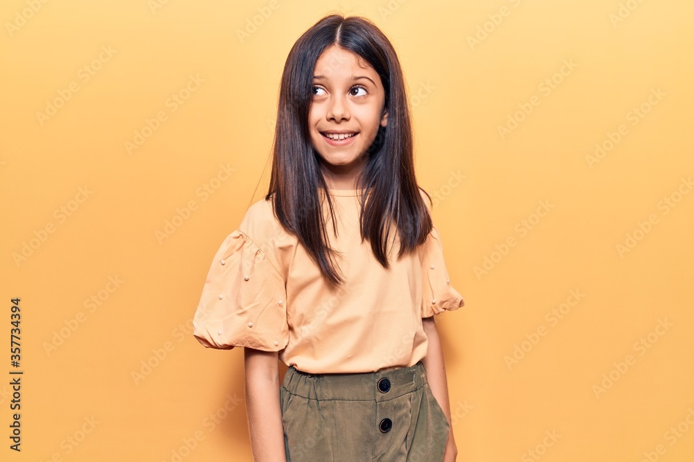 Beautiful child girl wearing casual clothes looking away to side with smile on face, natural expression. laughing confident. Beautiful child girl wearing casual clothes looking away to side with smile on face, natural expression. laughing confident.