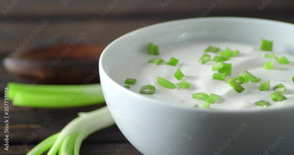 Sour cream with green onions in bowl rotates slowly. Sour cream with green onions in bowl rotates slowly.