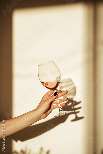 Glass of pink wine in hand with shadow on the wall photo