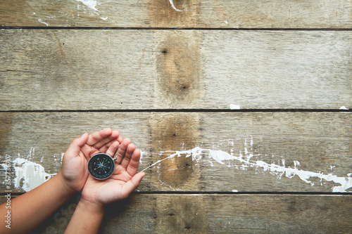 Child hands holiding compass on wooden photo