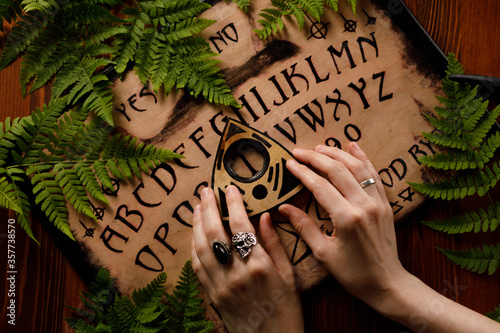 Mystic ritual with Ouija and candles. Devil's board concept, black magic or fortune telling rite with occult and esoteric symbols.