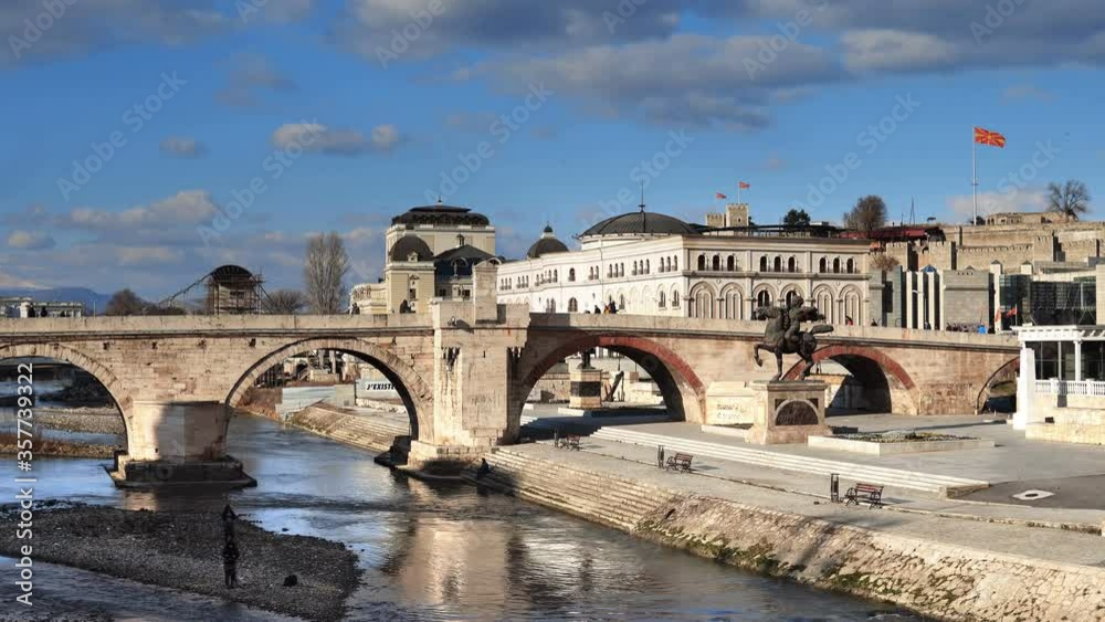 People walk at Stone Bridge at day in Skopje, Macedonia. The bridge is considered a symbol of Skopje People walk at Stone Bridge at day in Skopje, Macedonia. The bridge is considered a symbol of Skopje