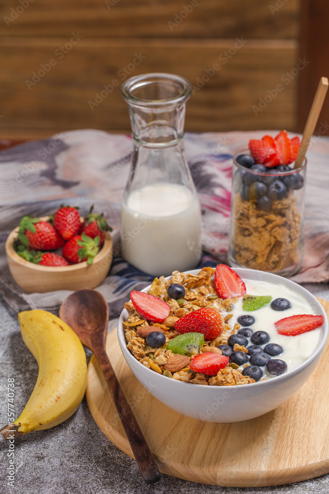 Homemade granola yogurt with fresh fruit and berries on breakfast table with banana and milk