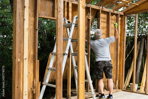 Valokuva Demolition phase with a man tearing down an old shed in a backyard that was rott