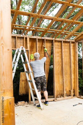 Demolition phase with a man tearing down an old shed with a crowbar in a backyard that was rotting and falling apart