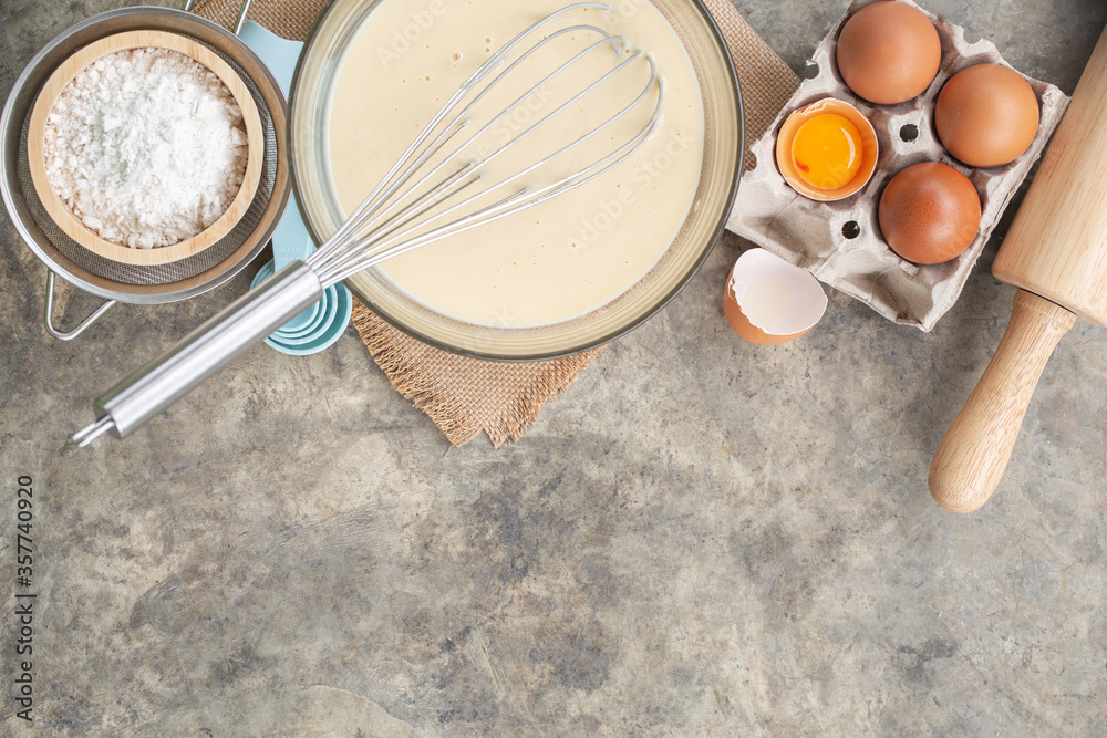Baking cooking Ingredients for pancake, flour eggs whisk on bright grey concrete background. Top view copy space. Baking cooking Ingredients for pancake, flour eggs whisk on bright grey concrete background. Top view copy space.