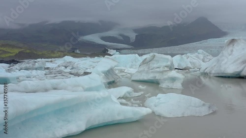 Aerial footage of blue icebergs in frozen lagoon, Fjallsárlón Iceland photo
