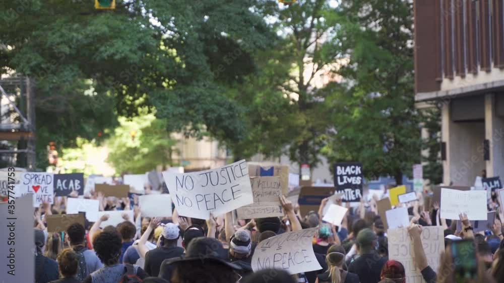 Protestors holding signs during a protest in city streets