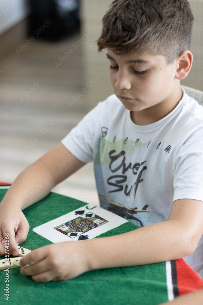 Garoto jogando dominó sobre a mesa de jogos Garoto jogando dominó sobre a mesa de jogos