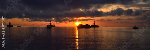Panoramic from the coast at sunrise with ships in the bay, cloudy sky and calm sea