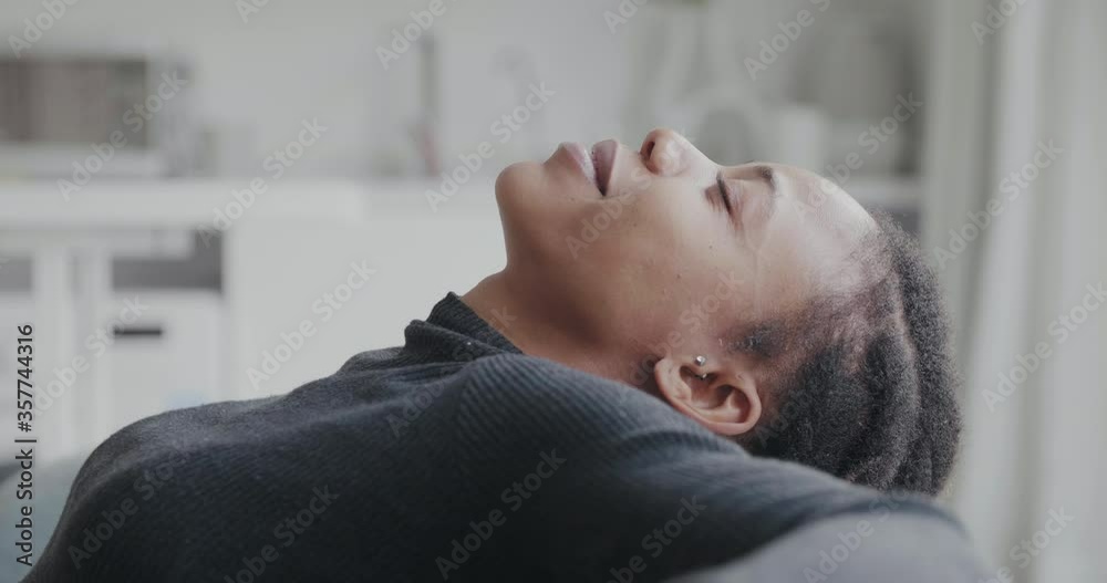 closeup of an african female face in profile closing eyes laughing happily shooting one side of a black lady imaging pleasant things enjoying life sitting on sofa smiling joyfully at home