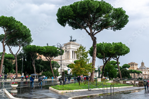 People walking on Via Dei Fori Imperiali Street. Monuments of Goddess Victoria riding on quadriga on top the Alter Of The Fatherland building in the background in Rome, Italy.
