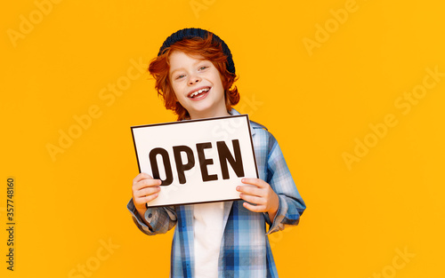 Happy ginger boy showing Open sign. © JenkoAtaman