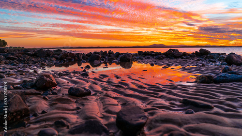 pink and orange skies reflecting on a pool of water on the beach