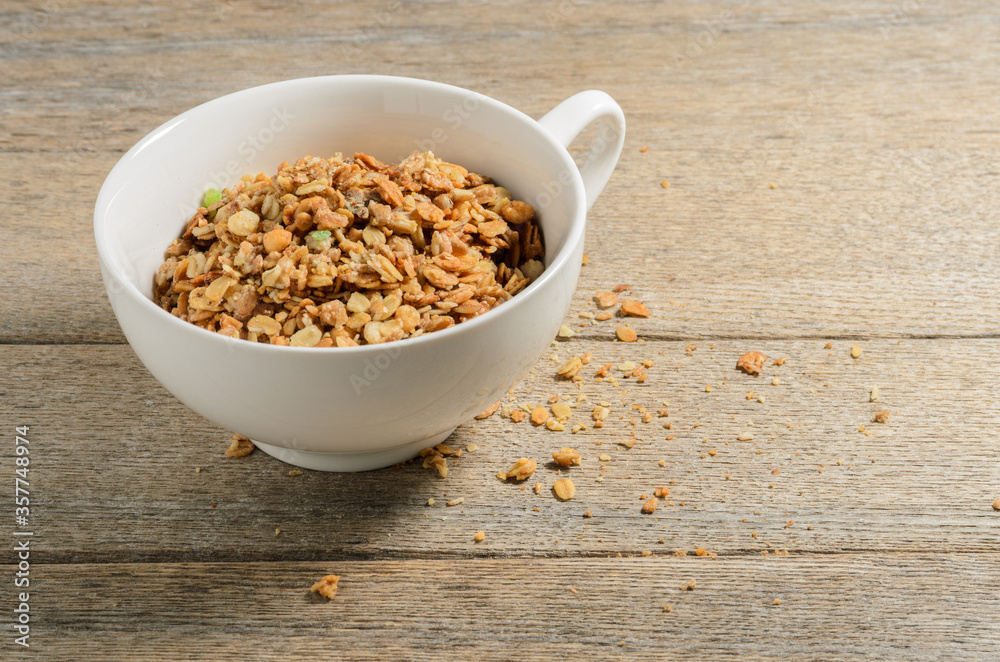 Muesli in a white bowl against the background of old village ash planks. Selective focus. Muesli in a white bowl against the background of old village ash planks. Selective focus.