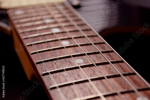closeup to a six electric guitar strings and wooden fretboards . Instruments and music concept