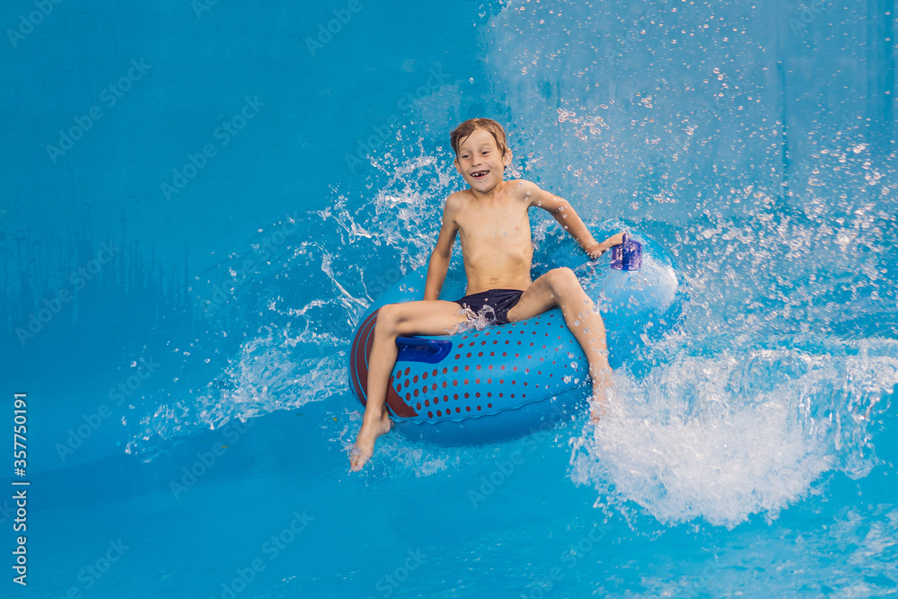 Boy on a pool float on artificial waves in a water park