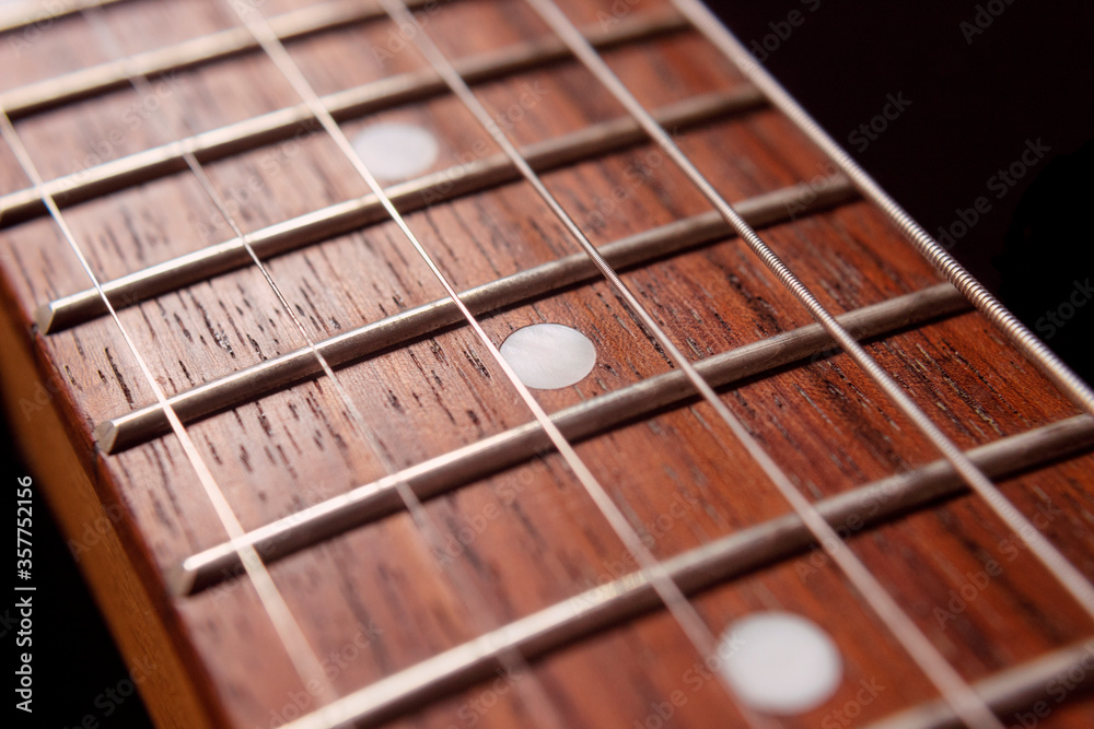 Macro photography to a six electric guitar strings and wooden fretboards. Vintage instruments and music concept