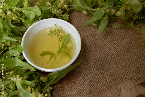 Tea from linden. Fresh flowering linden on a wooden background. Healthy and natural tea. June linden harvest. Healthy.