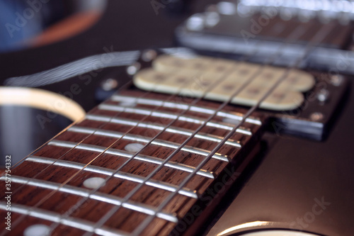 closeup to a six electric guitar strings, wooden fretboard and microphones . Instruments and music concept