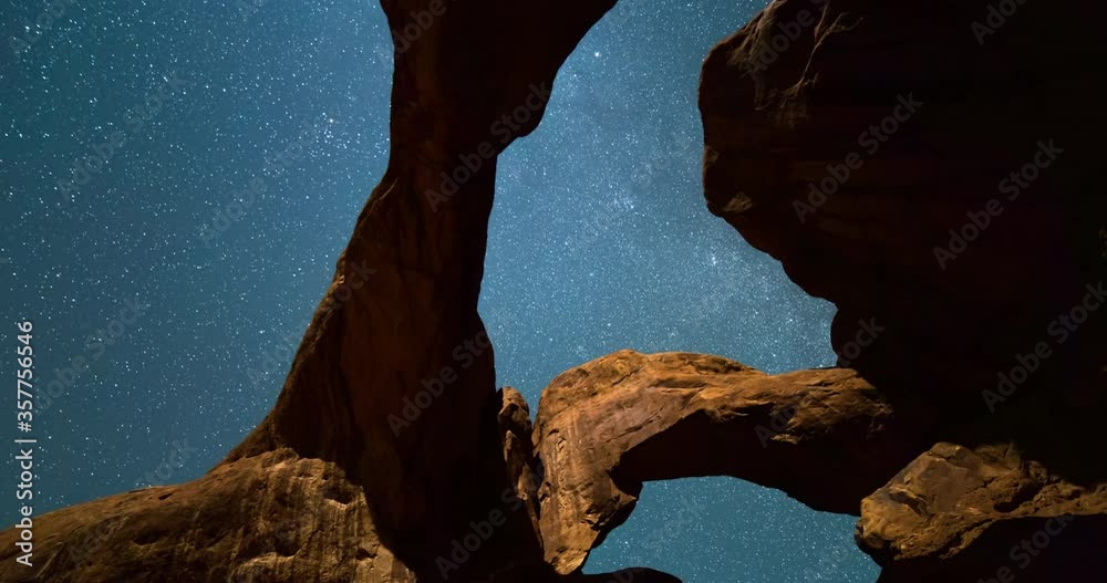 Tilt up time lapse shot of Double Arch in desert against constellation at night - Arches National Park, Utah