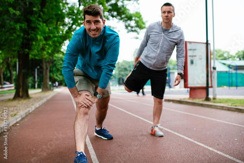 Young men exercising on a race track. Two young friends training outdoors.