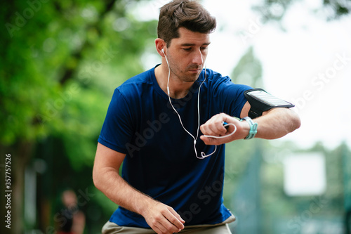 Young man checking his heart rate during work out. Young man exercising on athletics track