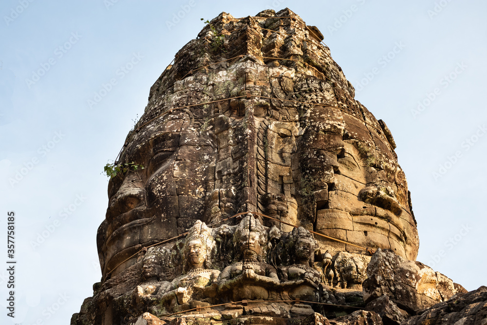 Close up of famous carved faces surrounded by khmer dancers on top of the Bayon temple in Angkor Thom, Siem Reap, Cambodia, South east Asia