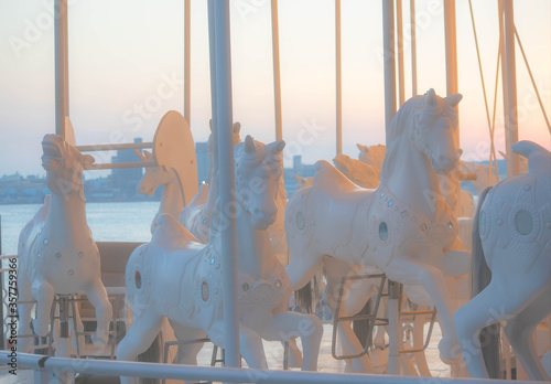 黄昏時の海辺の遊園地　ライトアップされた白いメリーゴーラウンド	 photo