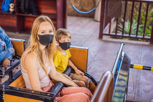 Mom and son on a roller coaster in medical masks after the coronovirus epidemic COVID 19