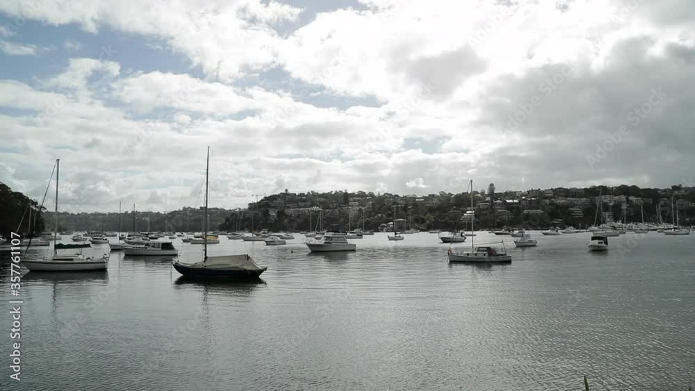 Sailboats moored in bay of seaside town on partly cloudy day, wide shot Sailboats moored in bay of seaside town on partly cloudy day, wide shot