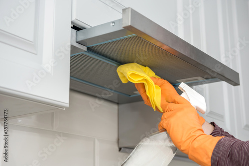 Quadro su tela male hands in protective gloves cleaning the kitchen hood with rag and spray bot