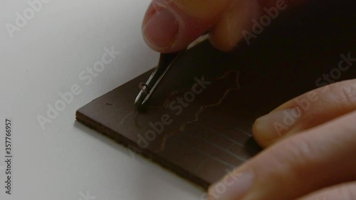 Close up slow motion view of lino block carving with metal tool. photo