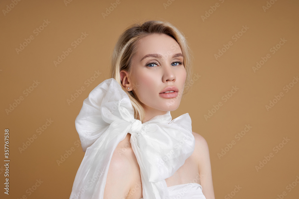 Beautiful blonde woman with a big white bow around her neck