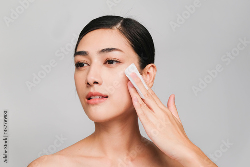 Young beautiful asian woman with clean, fresh and bright skin,holding Cotton swab with positive emotional,isolated on gray background,Beauty Cosmetics and Facial treatment Concept
