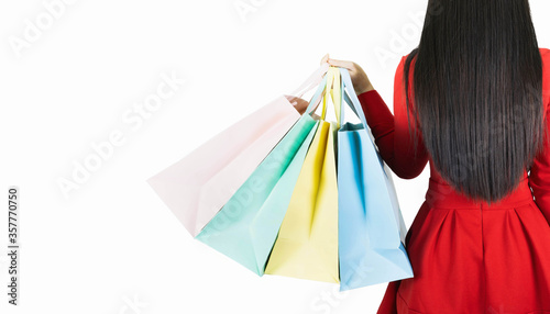 young beautiful woman in red dress carrying color pastel shopping bag isolated on white banner background with copy space