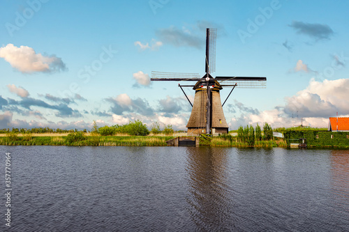 Reflection on a turbulent canal of a Dutch windmill landscape at Alblasserdam city during the warm sunrise