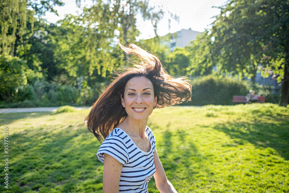 Young caucasian woman in the park with flying hair