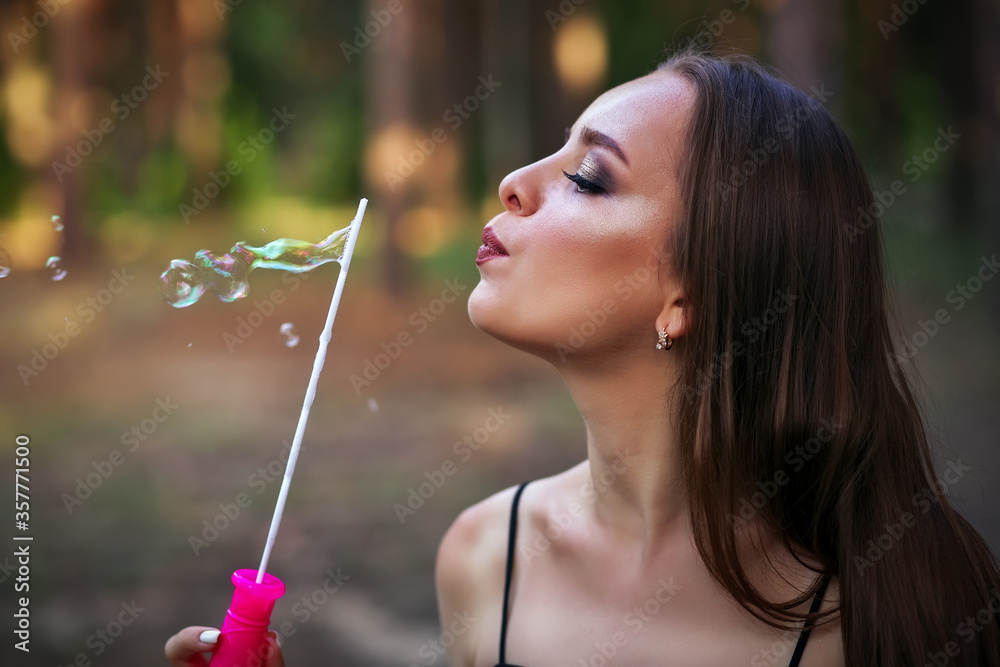 A happy girl blowing soap bubbles in summer park A happy girl blowing soap bubbles in summer park